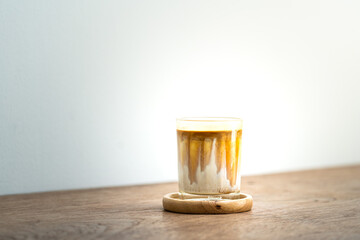 A glass of cold brew cappucino with milk fresh coffee which is served on the wooden table. Close-up and selective focus. Food and drink photo.
