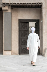 Naklejka premium arab man in traditional clothing walking in old Dubai