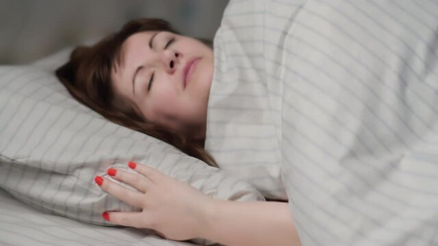 brunette woman puts her head on a pillow, woman did all the work and go to bed at night, woman with pleasure puts her head on the pillow