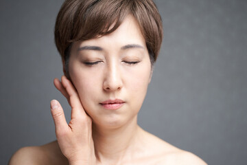 手の甲で頬を押さえる中年の日本人女性