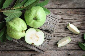 Fresh guava with green leaves on wooden background.