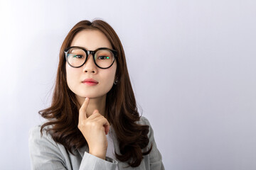 A young beautiful Asian woman in a suit has some thinking problem, or a lot of thought, holding her chin. Shoot over white background studio. Businesswoman vision and solution concept