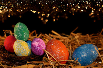 beautiful colorful Easter eggs lie on the straw with a shiny background
