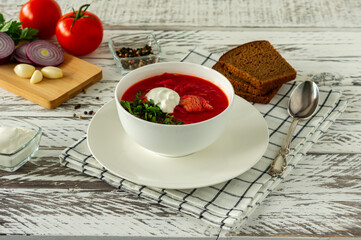Traditional Ukrainian Russian borscht with garlic and bread. A bowl of red beetroot borscht on a white wooden table. Beetroot soup. traditional slavic cuisine.