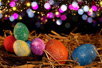 beautiful colorful Easter eggs lie on the straw with a shiny background