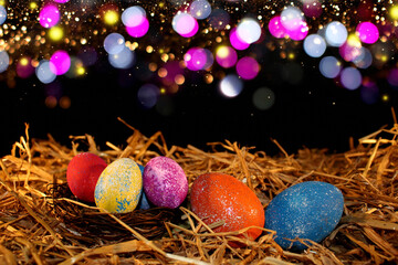 beautiful colorful Easter eggs lie on the straw with a shiny background