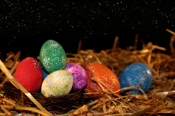 beautiful colorful Easter eggs lie on the straw with a shiny background