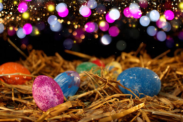 beautiful colorful Easter eggs lie on the straw with a shiny background