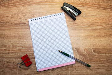  notepad a paper clip a stapler and a fountain pen are on the table