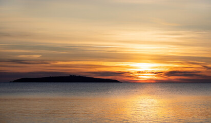 Fototapeta premium Sunrise on black sea. Clear water and colorful sky over island.