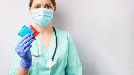 female doctor holds condoms in her hand. gray background, copy space.