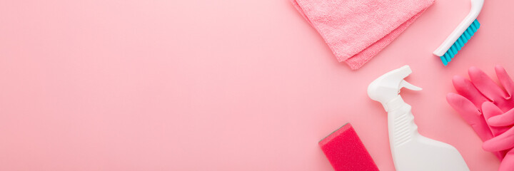 Simple cleaning set for different surfaces in kitchen, bathroom or other rooms. Spring regular cleanup. Light pastel pink background. Closeup. Top down view. Wide banner. Empty place for text or logo.