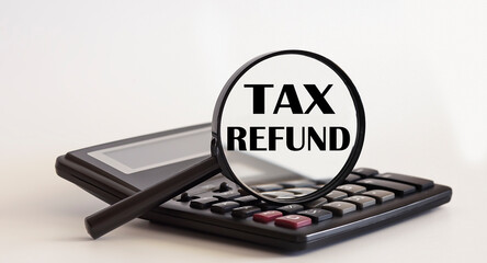 Focused on TAX REFUND concept. Magnifier glass with text on calculator. Business concept