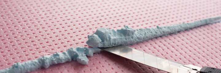 the master with a knife cuts off excess construction foam