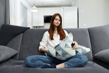 woman sitting on the couch in her free time with a pillow in her hands rest apartment interior
