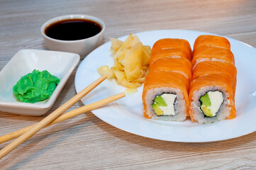 Rolls with fish avocado and cucumber in a plate with soy sauce and wasabi