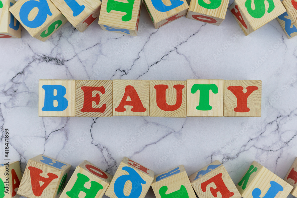Poster beauty concept with colorful alphabet letters on wooden cubes centered between top and bottom border
