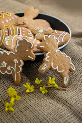 Easter holiday cookies servet on dish on the table with jute tablecloth, group of color painted gingerbread sweets springtime