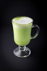 Matcha latte in a glass cup on black background.