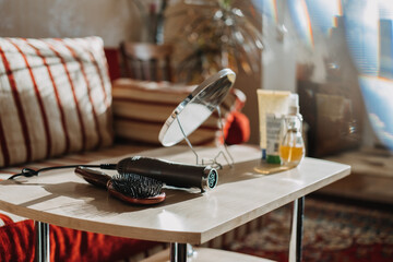 Style hair at home. Styling and treatments at home. Comb and hairdryer are on the table against the background of bottles of cosmetics