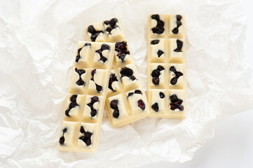 handmade chocolates mix, in the form of white chocolate bars with blueberries, top view, on a white background
