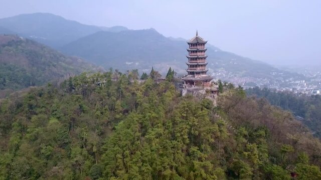 Aerial drone point of view of Dujiangyan, Chengdu, Sichuan, China. Mountain Qingcheng in the summer morning. Zoom out show up behind the woods mountain with pagoda tower on the hill top. Worship place