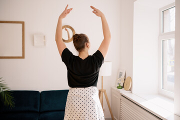 Teenager girl practicing ballet online classes at home. Woman dancing indoors