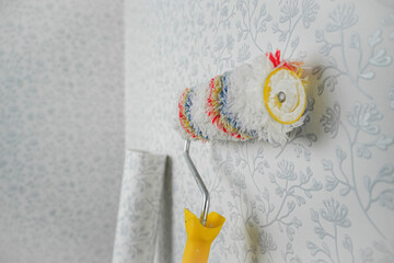 A long-haired roller stands near the wall for whipping wallpaper, a roller with a long handle