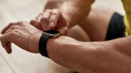 Workout results. Cropped shot of a mature man looking at his smart watch while exercising at home