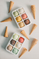 Set of organic ice cream balls and empty cones for filling. Mix of exotic fruit flavors and chocolate ice rolls. Colorful and tasty flat lay composition. Culinary top view. Summer food banner.