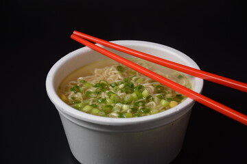 Noodles in plastic bowl, traditional asian meal on dark background, junk food concept