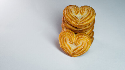 Close up of a little heart shaped biscuit placed in front of a vertical stack.