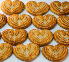 Obraz na płótnie Canvas Selective focus of little heart shaped biscuits arranged in a symmetrical pattern on a white background.