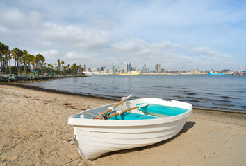 Naklejka na ściany i meble Lovely white boat on sandy beach with bay view and city