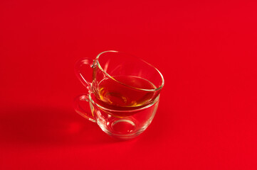 Two transparent glass cups on a red surface. Shot with soft shadow on red background with copy space