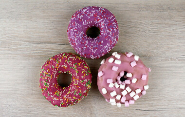 Round glazed donuts stacked in pyramid on wooden background