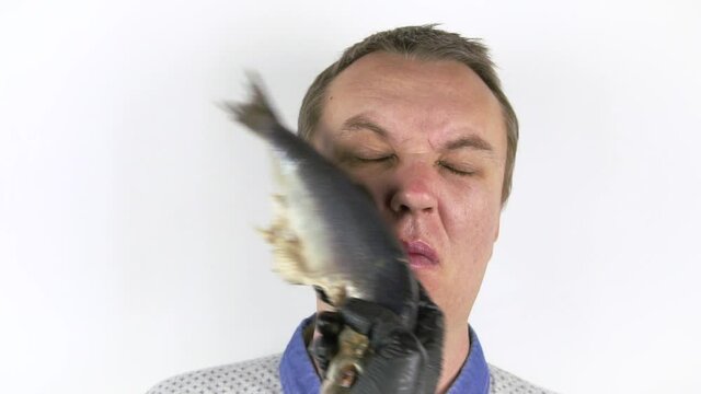 Fresh herring hits a young man's face. Funny man gets slapped in the face with wet fresh fish.the concept of a quarrel, a video blogger Challenge