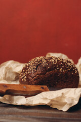 rye bread on paper packaging on a red background and a wooden table with a sharp knife