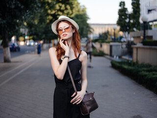 beautiful woman in a black dress walks in the park and green trees in the background