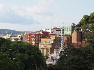 Colored townscape of european city of Barcelona at Catalonia district in Spain and chimney of entrance building to Park Guell, cloudy blue sky in 2019 warm sunny summer day on September.