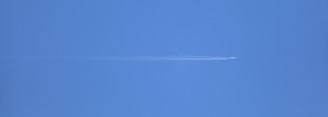 white trail white jet plane in the blue sky