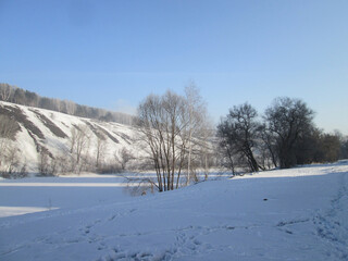 frozen riverbed in winter in the snow with a cliff on the bank of the hill nature in Siberia