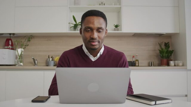 Young african american student achieves a milestone while studying a class on a laptop. Black man browsing through a web shop and liking items and nods