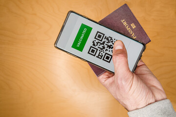 Tourist holding a passport and a Green pass certificate of vaccination. Meaningless QR code.The European Union will propose issuing a certificate called a Digital Green Pass