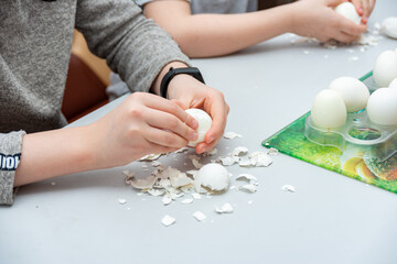 Children peel boiled eggs from their shells for making salads.
