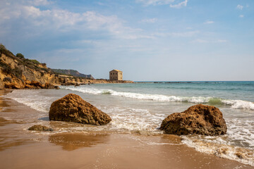 View of the Le Pergole beach in Sicily. The colorful rocks contrast beautifully with the color of the sea. A warm summer afternoon.