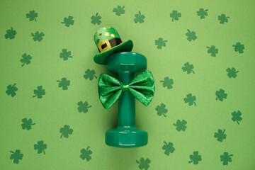 Heavy dumbbell wearing Irish shamrock leaf clover hat and a bow tie. Healthy fitness gym flat lay...