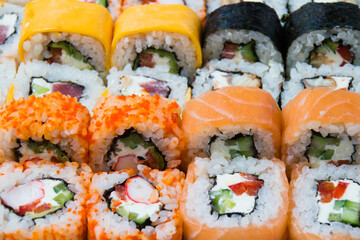 Big set of sushi rolls with avocado eel, salmon, chedar cheese, crab stick, caviar, tuna, nori, cucumber and cream cheese close-up