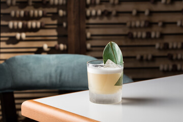 sour muddy alcohol cocktail with foam and sesame seeds in a glass on thetable at restaurant