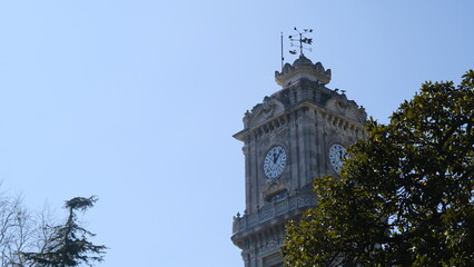Fototapeta na wymiar Old and ancient ottoman architecture and style clock tower in front of dolmabahce palace in İstanbul near bosphorus sea during sunny day. 03.03.2021. İstanbul Turkey.